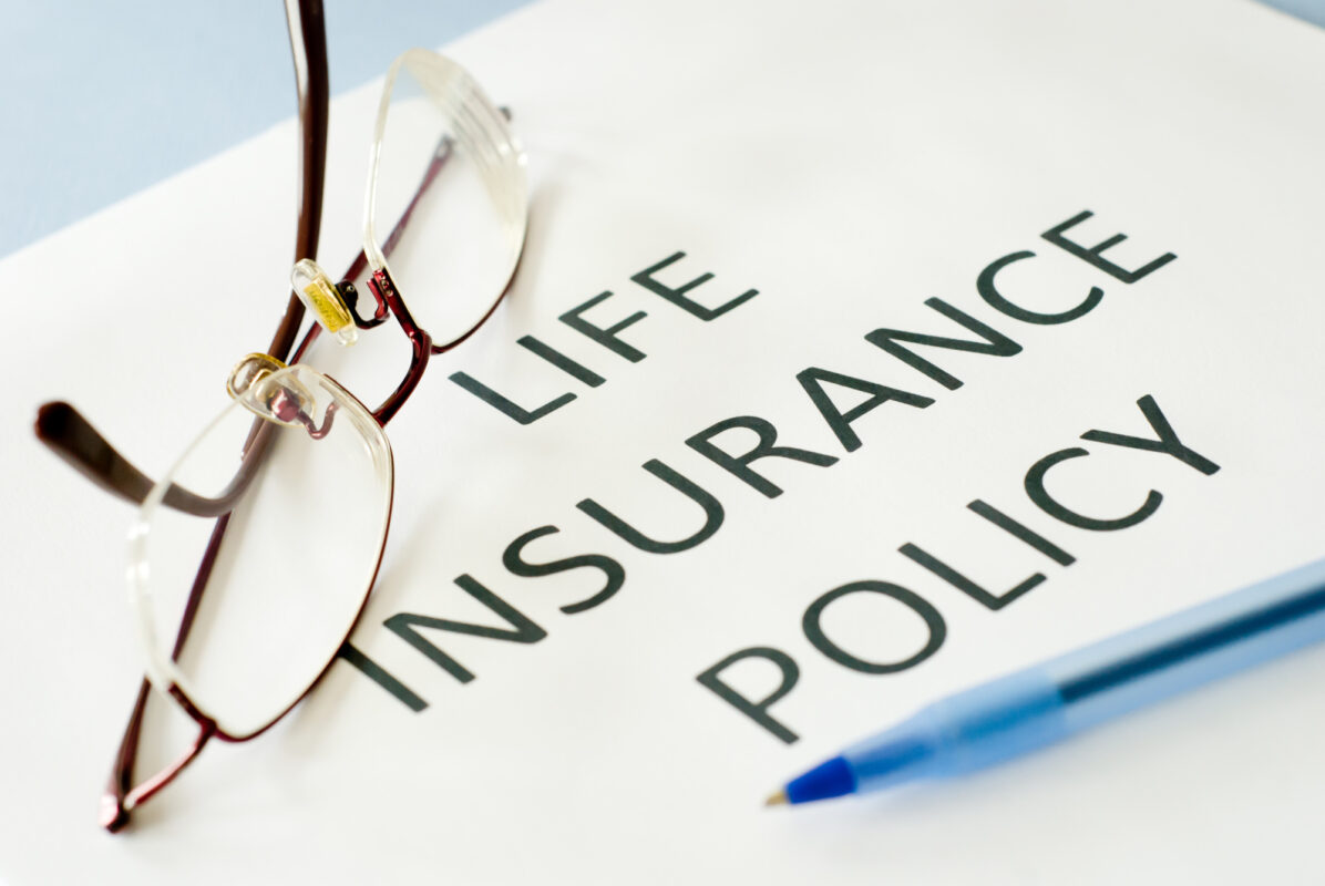  A person wearing glasses is reading a document titled 'Life Insurance Policy'.