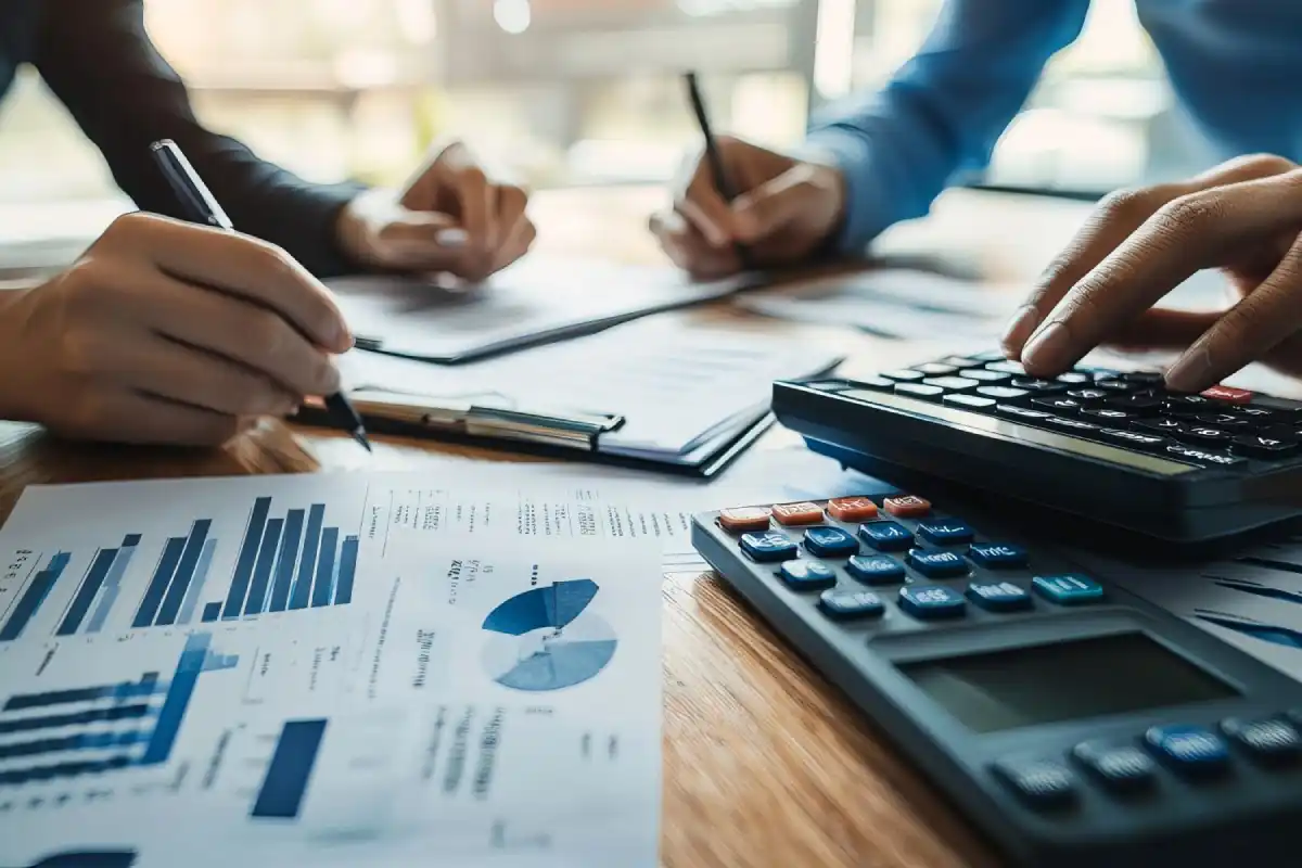people collaborating on financial reports with calculators and charts on desk